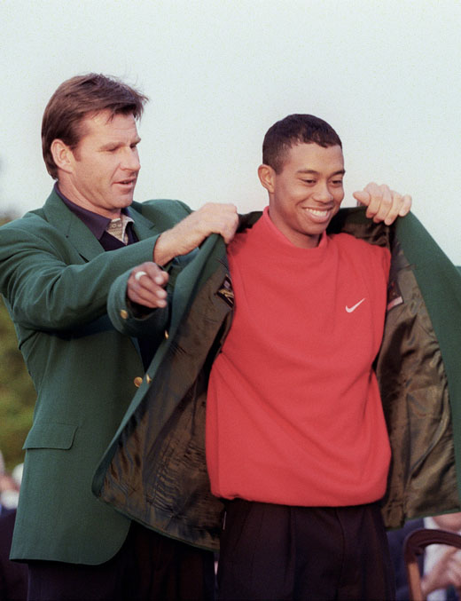 1997 Handover: Nick Faldo presents a 21-year-old Tiger Woods with the first of his four green jackets.
