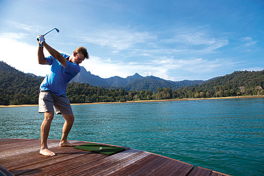 Ernie Els tees off from the back of a yacht towards the Els Club Teluk Datai
