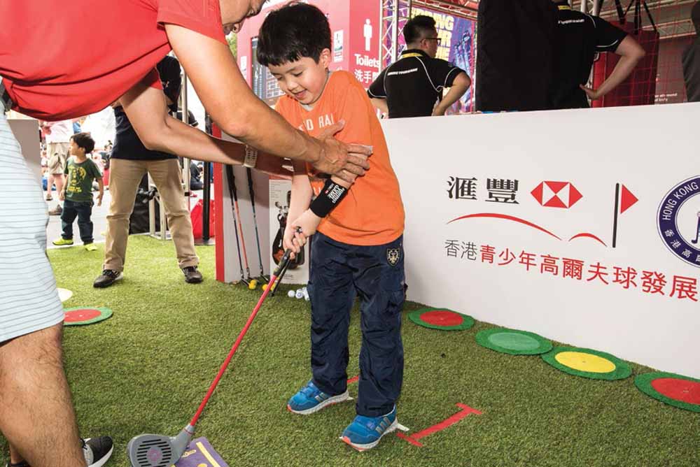 A young rugby fan tries golf for the first time at the Hong Kong Golf Association’s Junior Golf Challenge in the HSBC Sevens Village