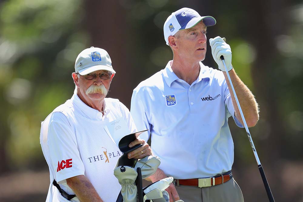 Jim Furyk pulls a club from his bag as caddie Mike "Fluff" Cowan looks on