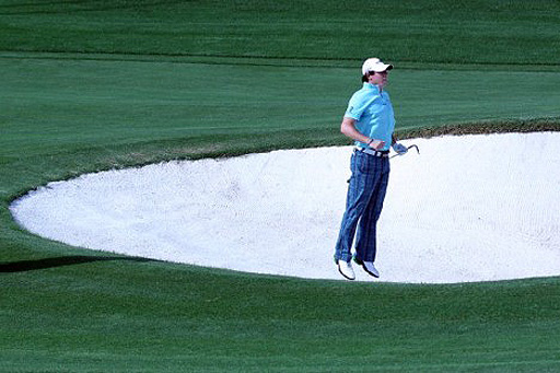 McIlroy reacts after hitting out of a bunker in his first round